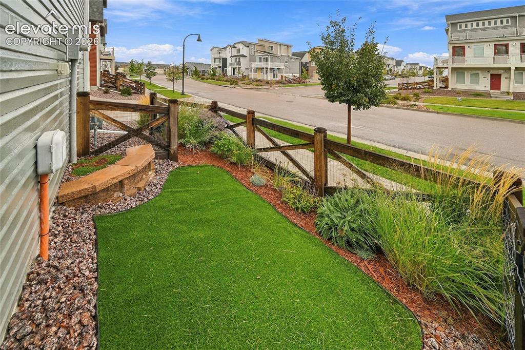 Image 4 of 30: Exterior landscaping featuring artificial turf, a stone-built bench, and a 