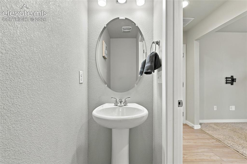 Image 8 of 30: Pedestal sink with chrome faucet, an oval mirror, and wall-mounted lighting