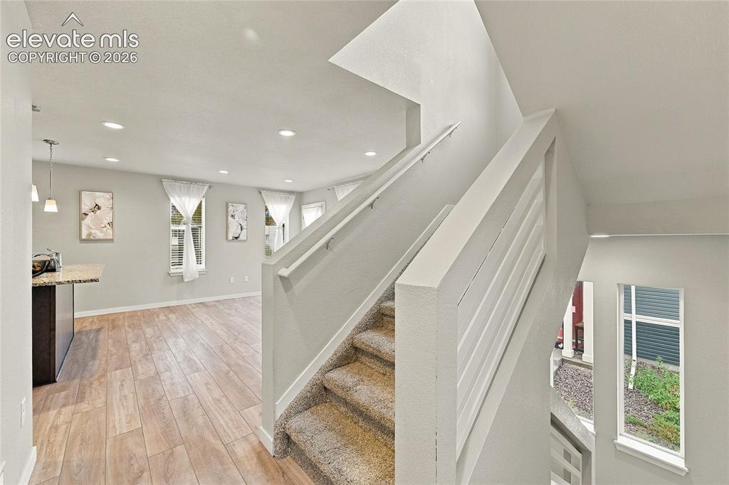Image 9 of 30: Wood-finish flooring, recessed lighting, and a modern horizontal baluster s