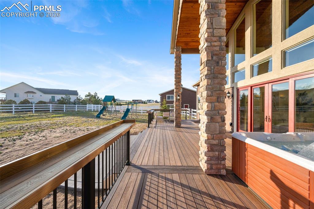 Image 31 of 50: Deck with custom pillars and 2 story overhang matching the ceiling inside