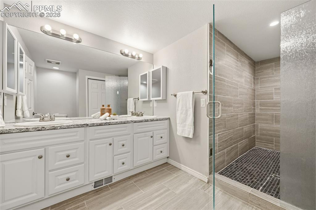 Image 42 of 50: Bathroom attached to bed 5 has double sinks and huge walk in shower