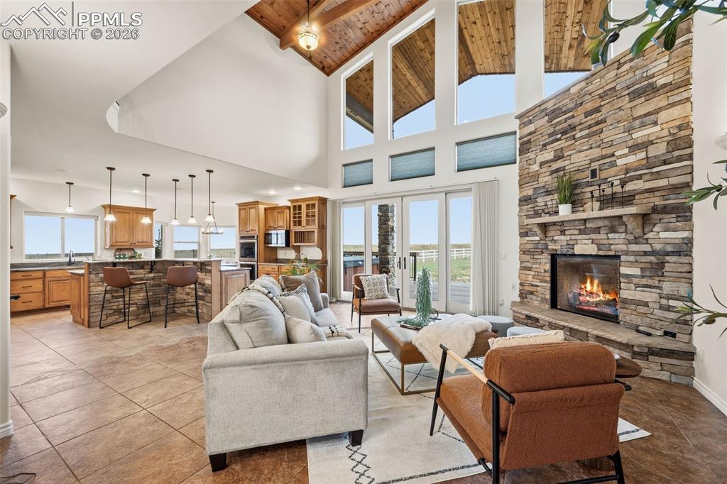 Image 9 of 50: Stone fireplace extends up, ceramic tile floor, 2 story great room