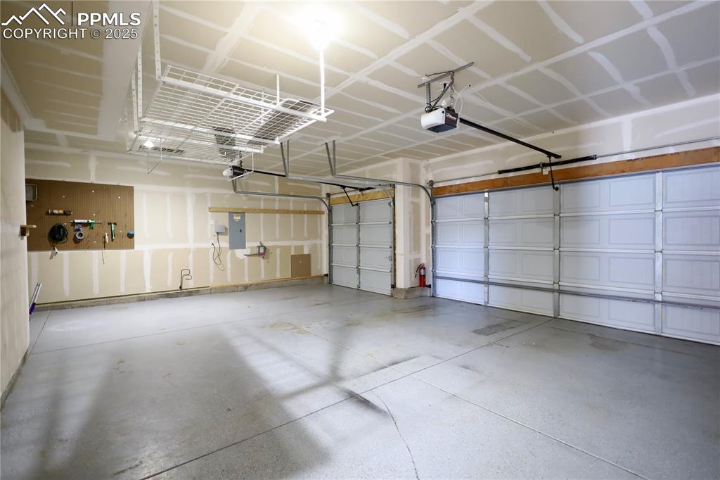 Image 32 of 41: Garage with electric panel, a garage door opener, and a carport