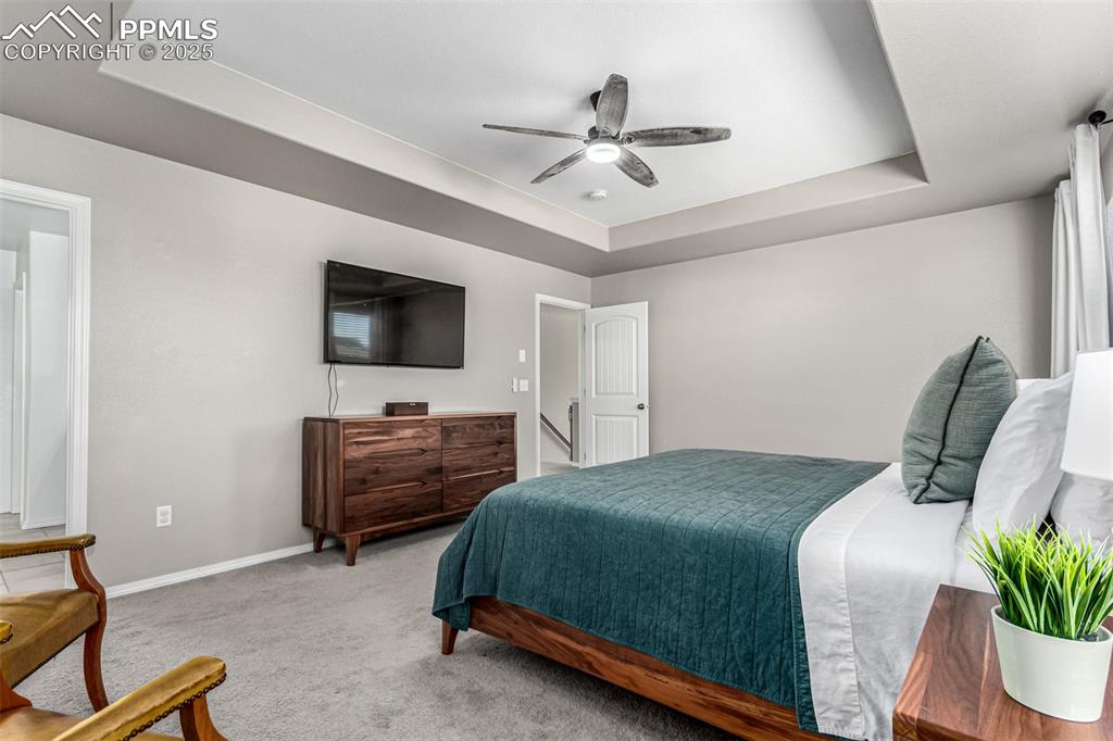 Image 18 of 41: Carpeted bedroom featuring a raised ceiling and a ceiling fan