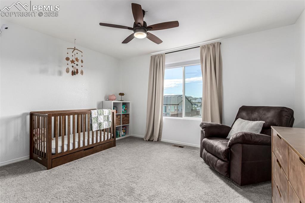 Image 21 of 41: Bedroom with a crib, carpet flooring, and ceiling fan
