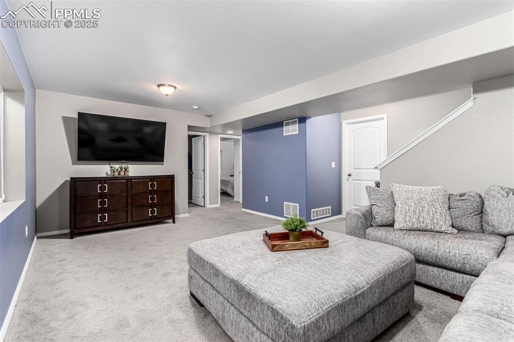 Image 28 of 41: Living area with light colored carpet and stairway