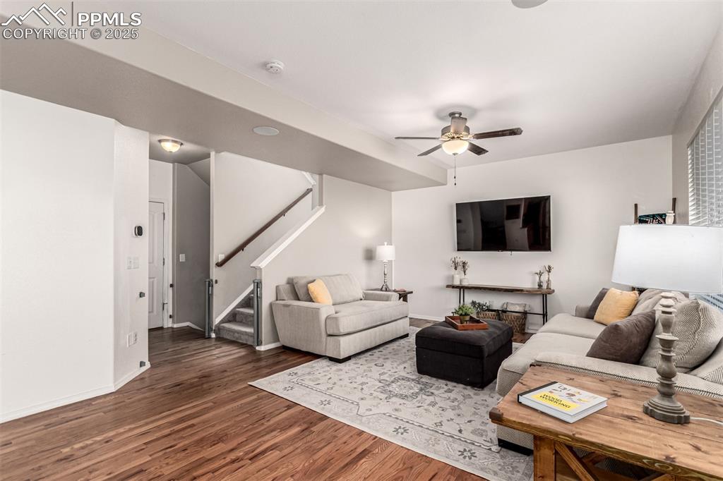 Image 6 of 41: Living area with stairway, dark wood-type flooring, and a ceiling fan