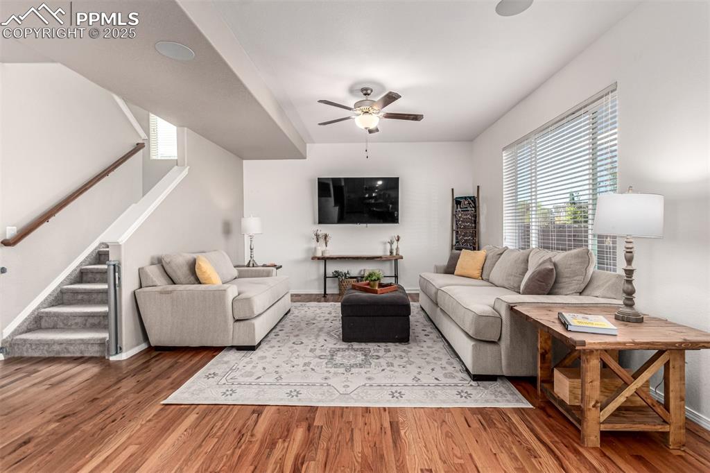 Image 8 of 41: Living room featuring stairs, wood finished floors, and a ceiling fan