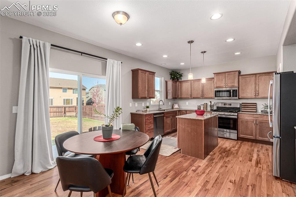 Image 9 of 41: Kitchen with hanging light fixtures, a center island, appliances with stain