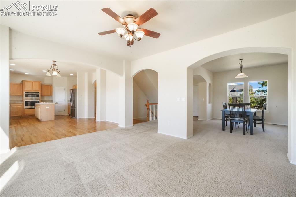 Image 13 of 50: Unfurnished living room with light colored carpet, a ceiling fan, a chandel