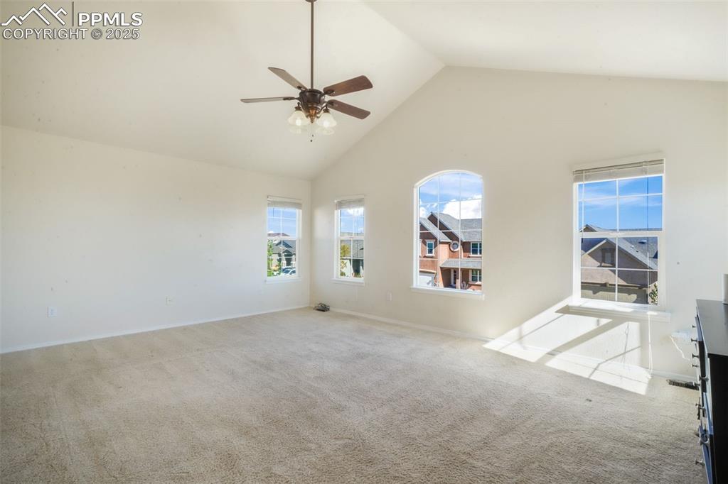 Image 18 of 50: Unfurnished room with high vaulted ceiling, carpet, and a ceiling fan