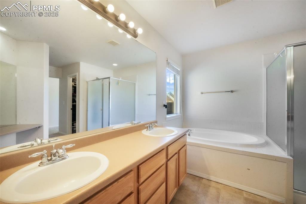 Image 25 of 50: Full bathroom with a garden tub, double vanity, a shower stall, and light t