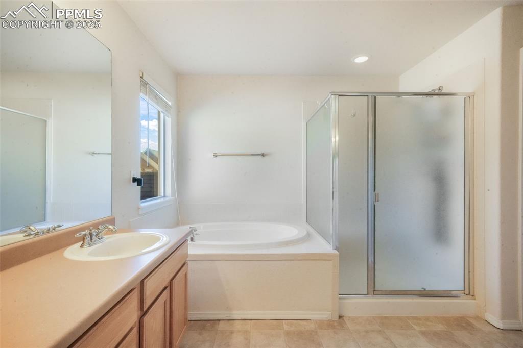 Image 26 of 50: Full bath featuring a garden tub, vanity, and a stall shower