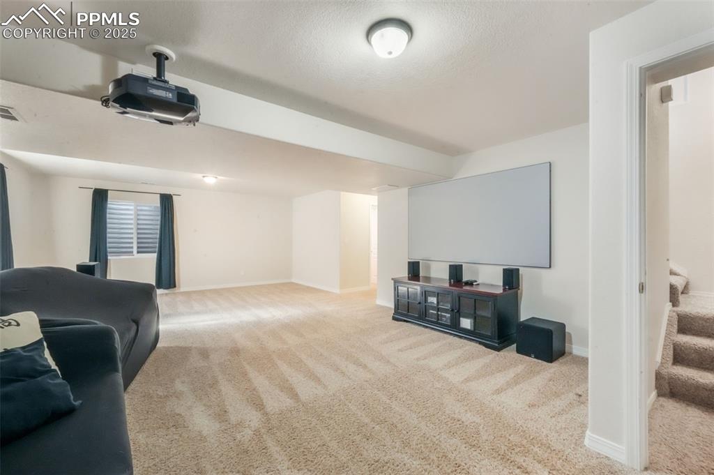 Image 38 of 50: Carpeted cinema with baseboards and a textured ceiling