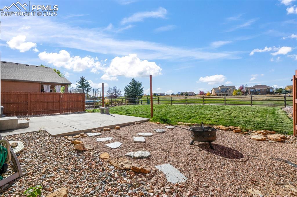 Image 47 of 50: Fenced backyard with an outdoor fire pit and a patio area