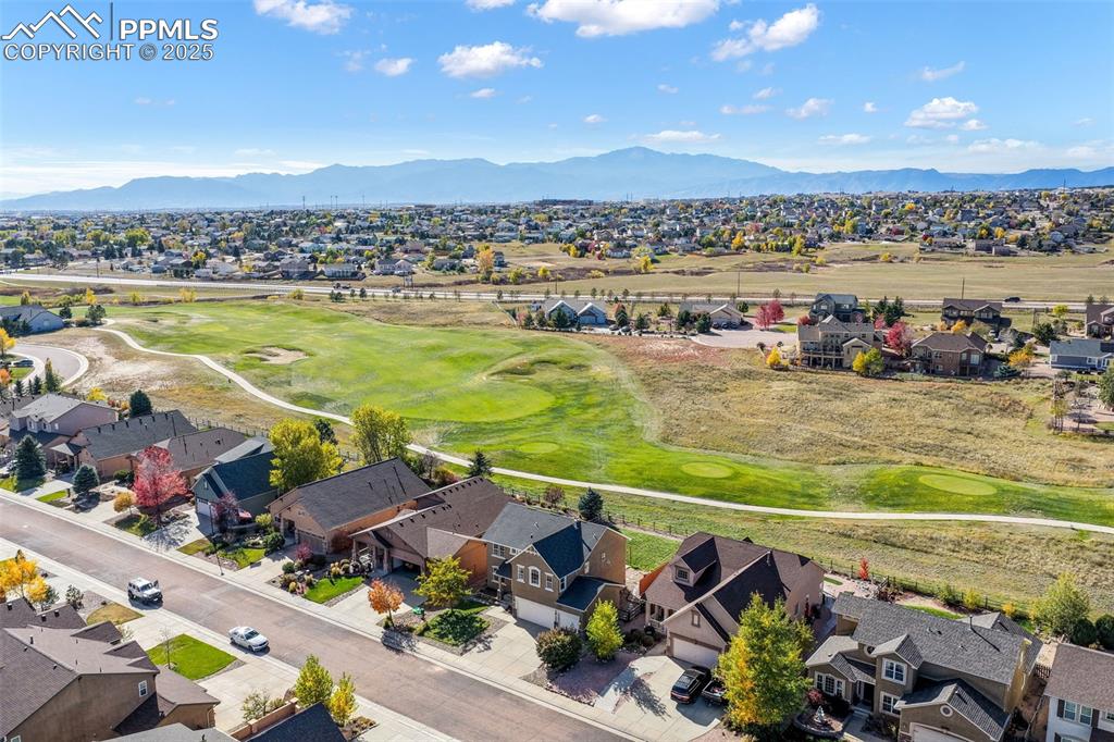 Image 49 of 50: Aerial view of residential area featuring a golf course and a mountainous b