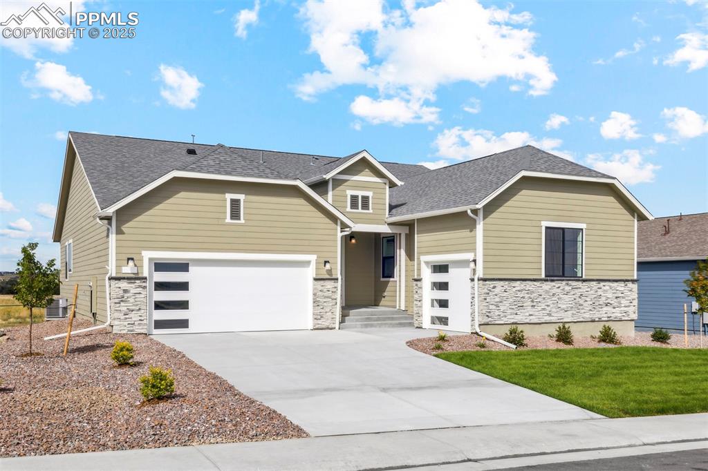 Caption: Craftsman house with cooling unit, stone siding, a front lawn, and concrete driveway