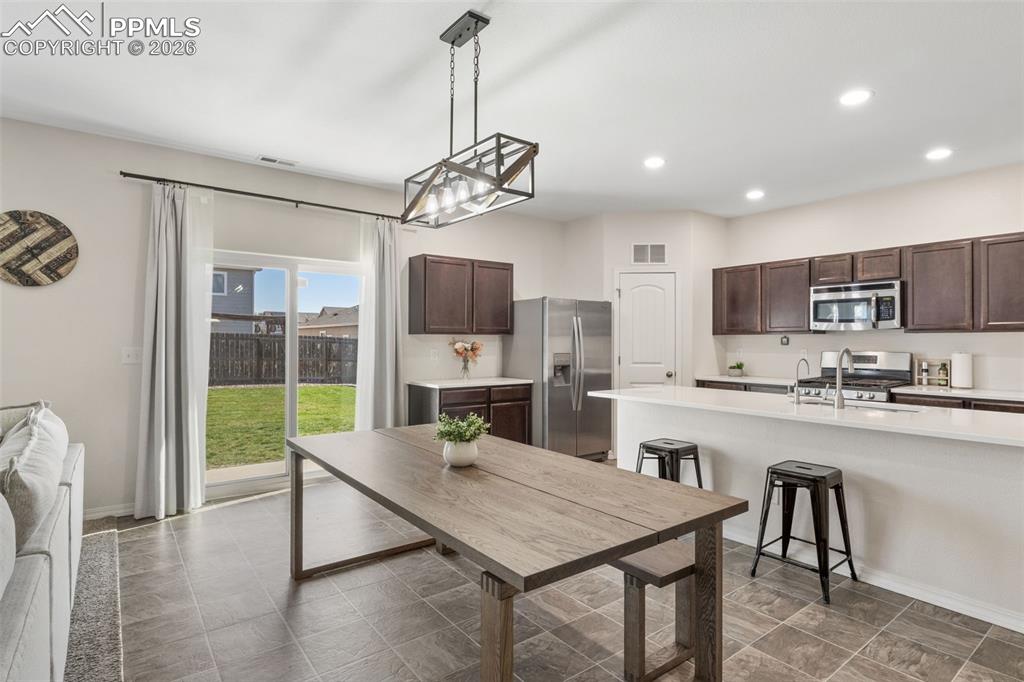 Image 10 of 25: Open-concept kitchen and dining area featuring ceramic tile flooring, dark 