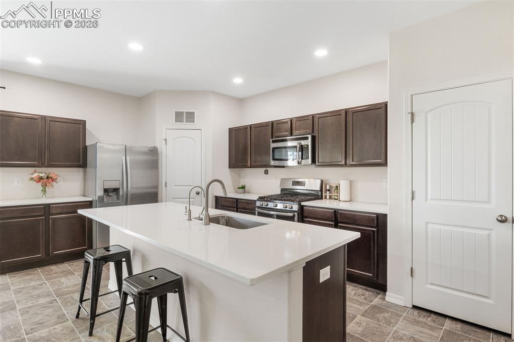 Image 11 of 25: Modern kitchen featuring dark wood cabinetry, stainless steel appliances, a