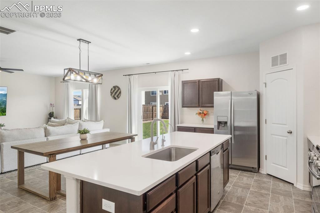 Image 2 of 25: Kitchen island with a white countertop and integrated stainless steel sink,