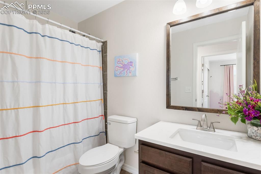 Image 20 of 25: Bathroom featuring a white vanity with an integrated sink, a large framed m