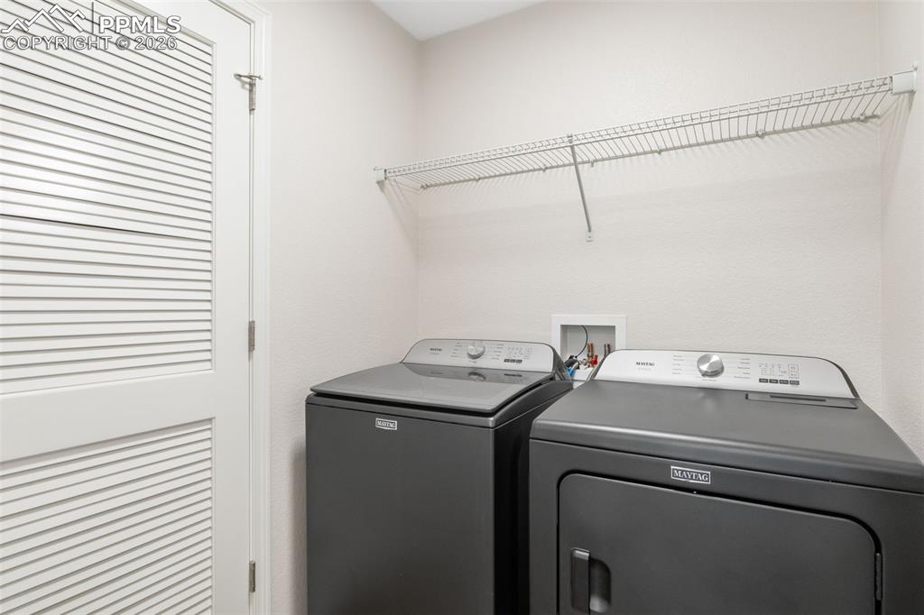 Image 23 of 25: Dedicated laundry area featuring a louvered bi-fold door, wire shelving, an