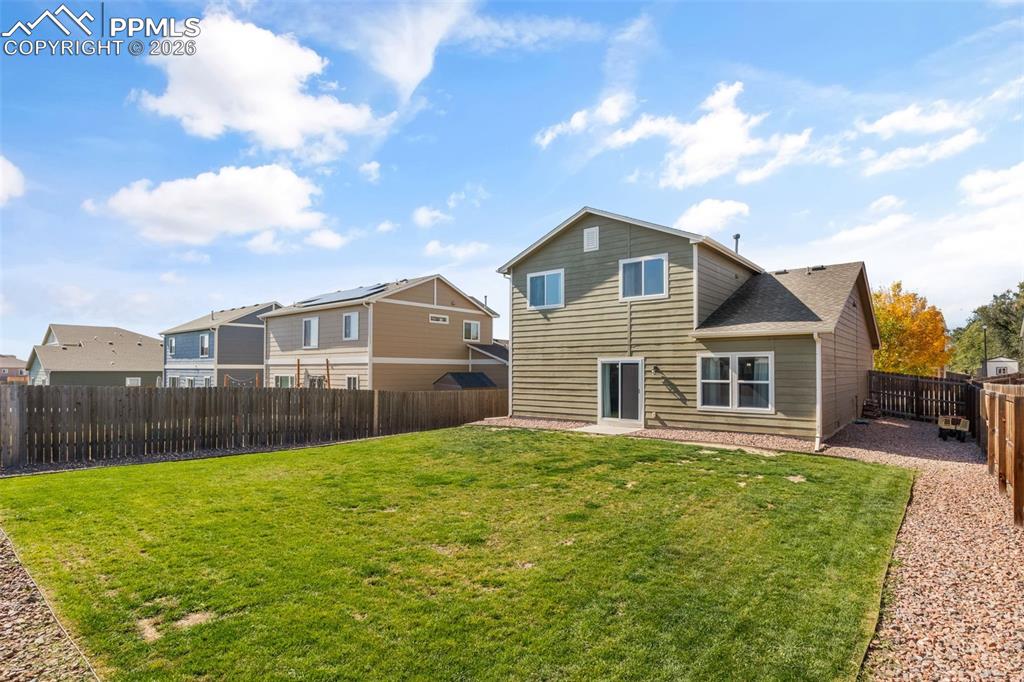 Image 25 of 25: Expansive backyard featuring a manicured lawn, a gravel path, and a wooden 