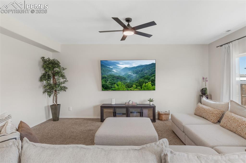 Image 9 of 25: Carpeted living area featuring a ceiling fan with integrated lighting, a wa