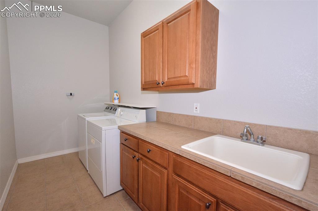 Image 18 of 50: Laundry room on main level with utility sink/cabinets