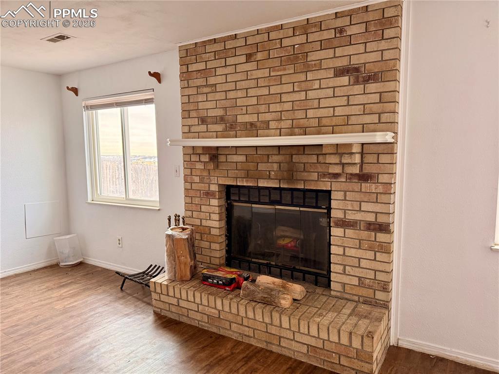 Image 25 of 42: Detailed view of a brick fireplace and wood finished floors