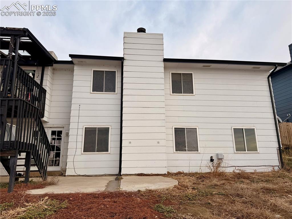 Image 40 of 42: Back of house featuring a patio area, stairs, and a chimney