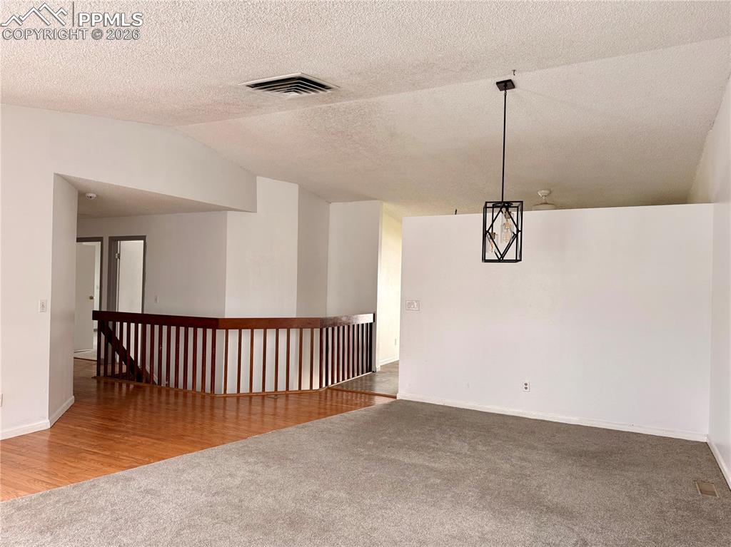 Image 6 of 42: Empty room with light colored carpet, lofted ceiling, a textured ceiling, a