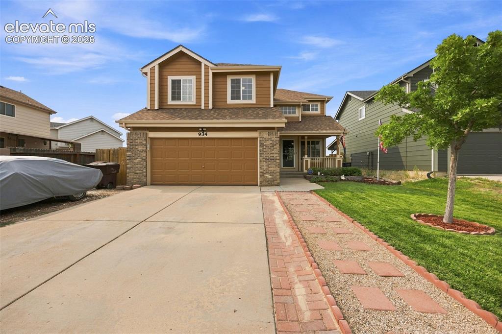 Caption: Two-story residence featuring a two-car garage with a brown door, stone accents on the facade, and a