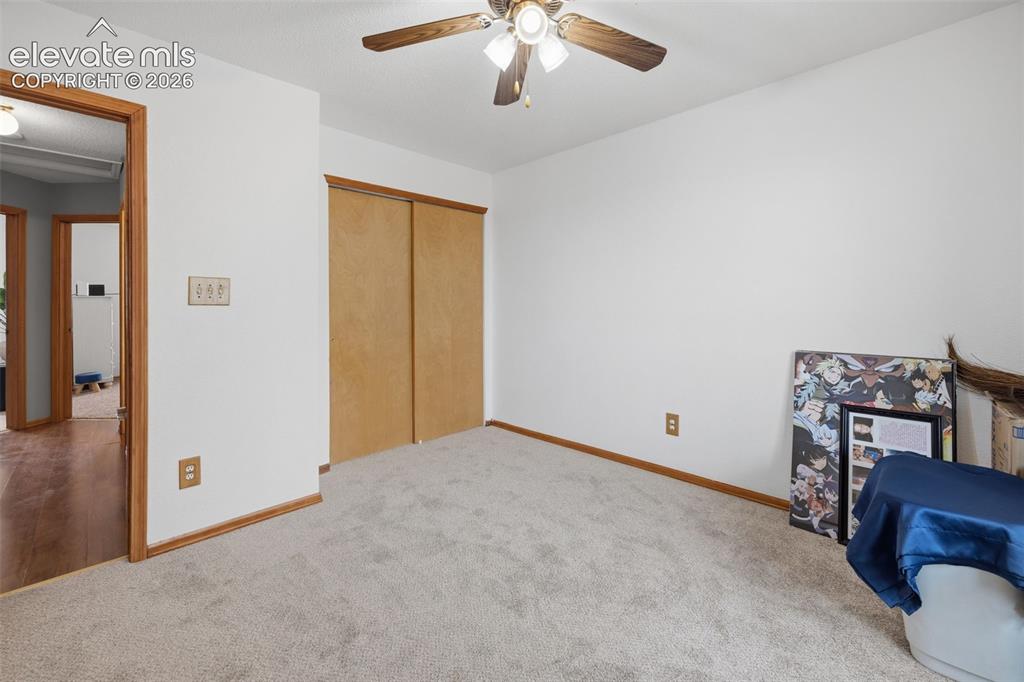 Image 13 of 27: Primary Bedroom featuring a ceiling fan with light fixture, wood-trim windo