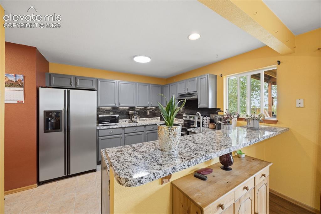 Image 6 of 27: Living area featuring wood-finish flooring, a corner fireplace with a tiled