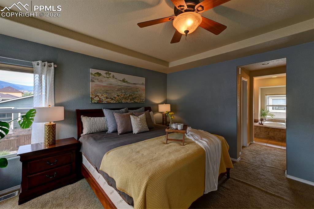 Image 14 of 33: Tray ceiling and ceiling fan enhance the primary suite, with direct entry i