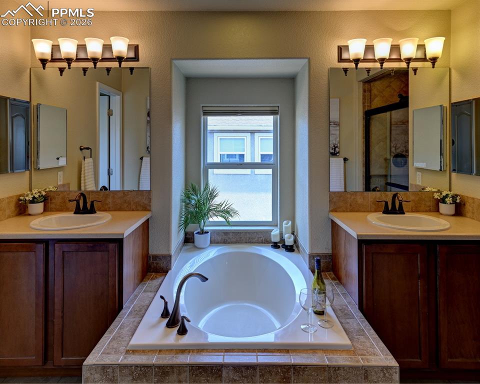 Image 16 of 33: Spa inspired bath with soaking tub framed by dual vanities