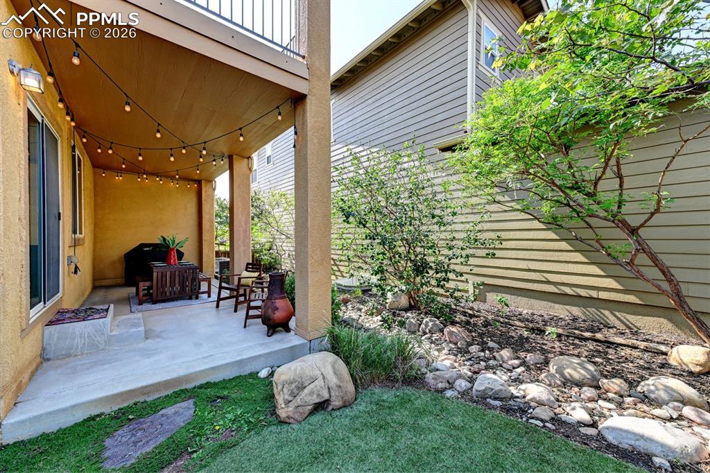 Image 18 of 33: Covered patio opens to mature trees and side yard, offering added space and