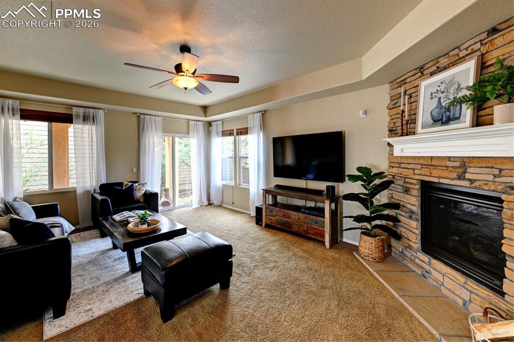Image 6 of 33: Light filled living room with stone faced gas fireplace and seamless indoor