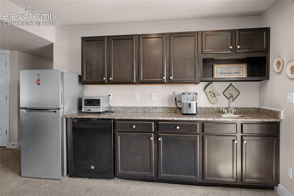 Image 35 of 47: Kitchenette has a bar sink, refrigerator and wine cooler