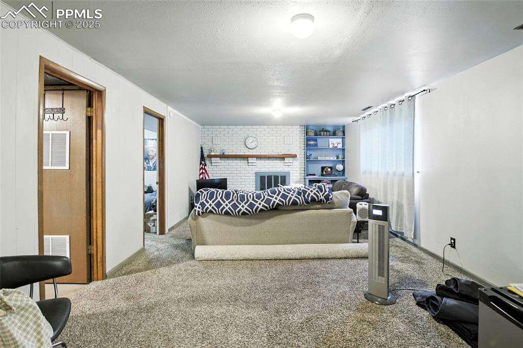 Image 23 of 35: Carpeted bedroom featuring a textured ceiling and a brick fireplace
