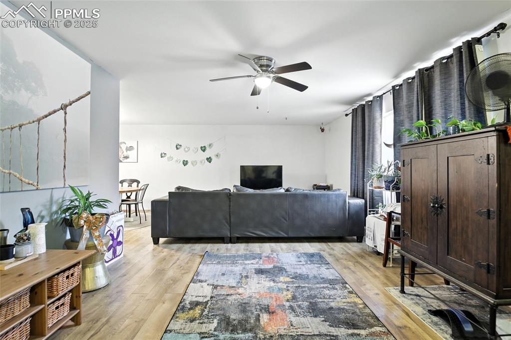 Image 6 of 35: Living area featuring light wood finished floors and a ceiling fan