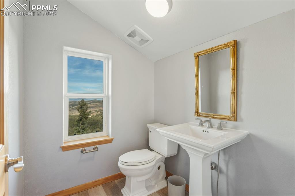 Image 20 of 50: Half bathroom featuring vaulted ceiling and wood finished floors