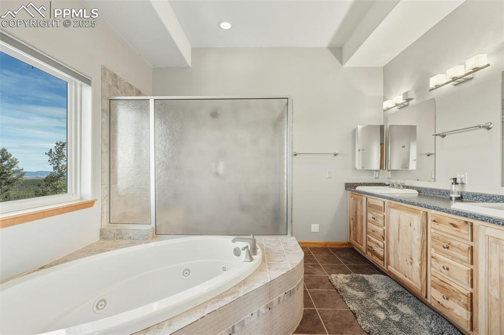 Image 26 of 50: Full bath with a tub with jets, double vanity, dark tile patterned flooring