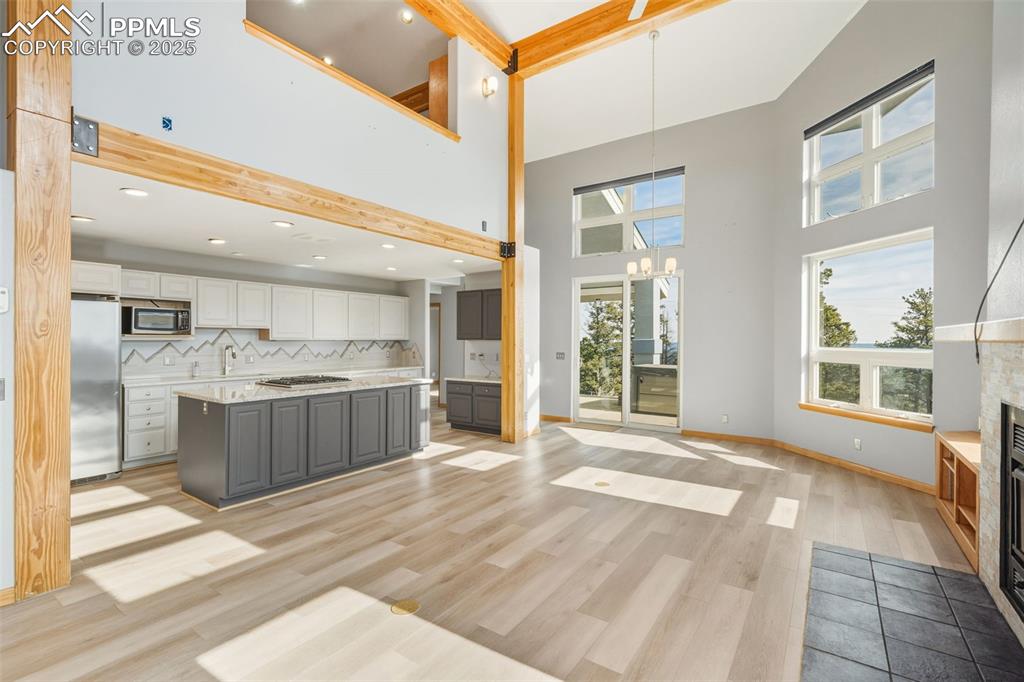 Image 41 of 50: Kitchen featuring a glass covered fireplace, decorative backsplash, gray ca