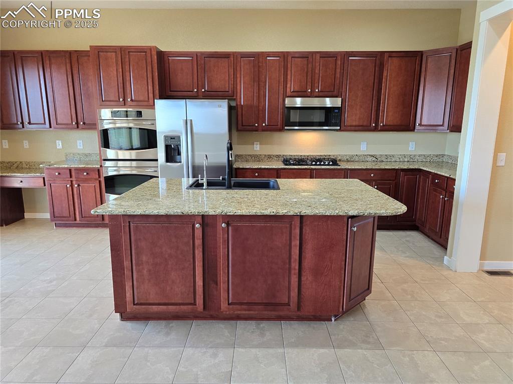 Image 2 of 27: Kitchen with dark brown cabinets, appliances with stainless steel finishes,