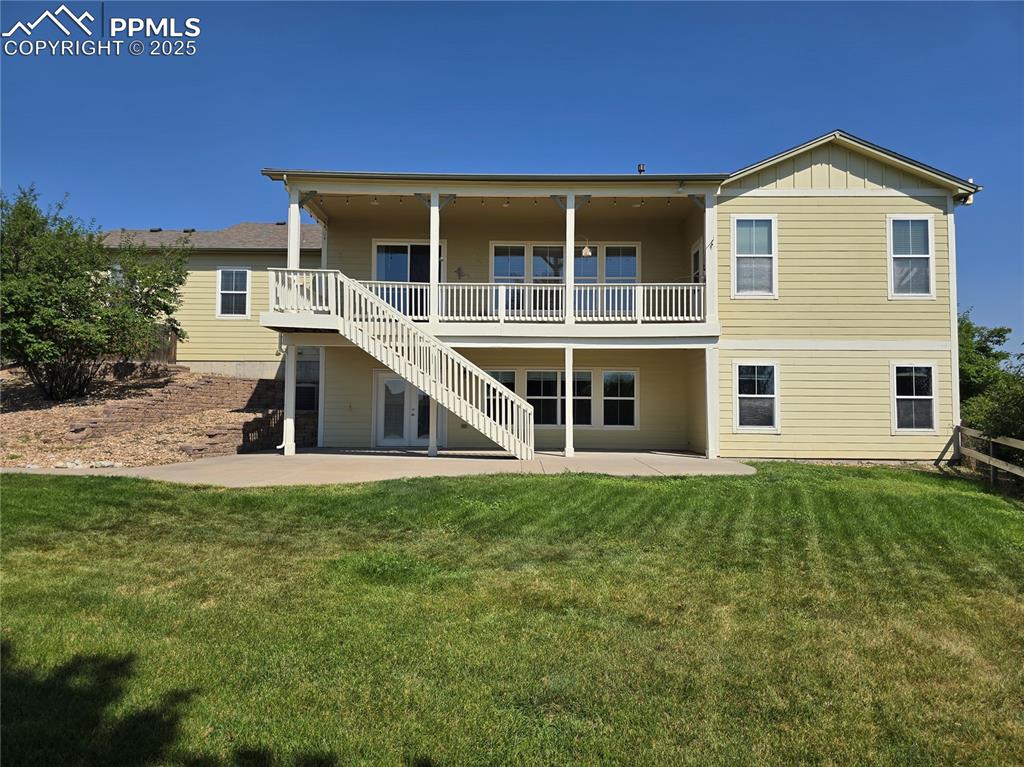 Image 21 of 27: Back of house with a patio, stairs, a lawn, and board and batten siding