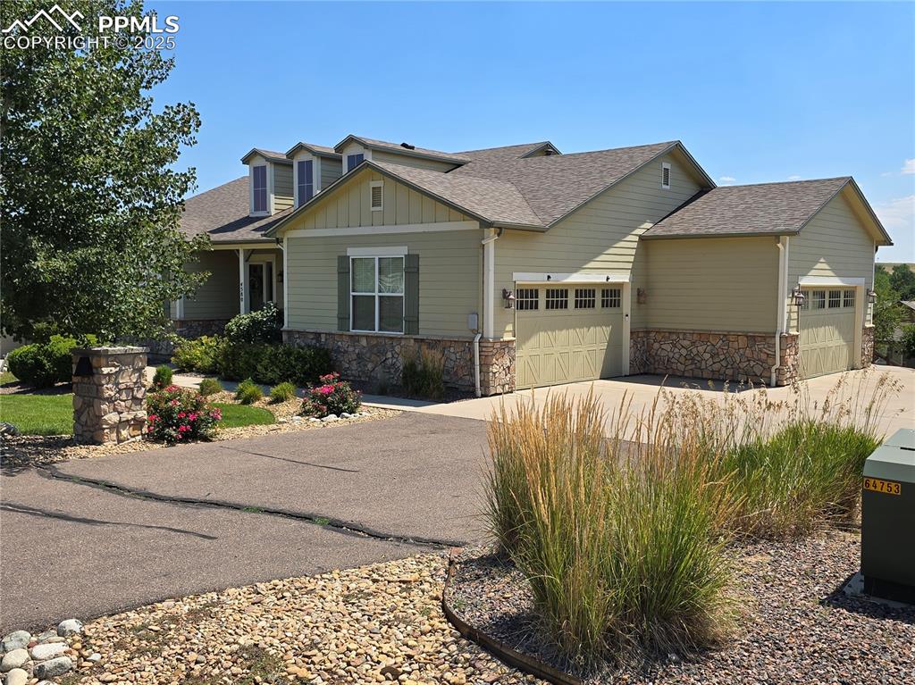 Image 27 of 27: Craftsman-style home with a shingled roof, stone siding, concrete driveway,