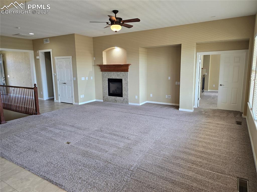 Image 7 of 27: Unfurnished living room with a tile fireplace, a ceiling fan, and light col