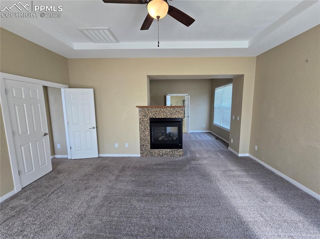 Image 9 of 27: Unfurnished living room featuring a fireplace, carpet flooring, a ceiling f